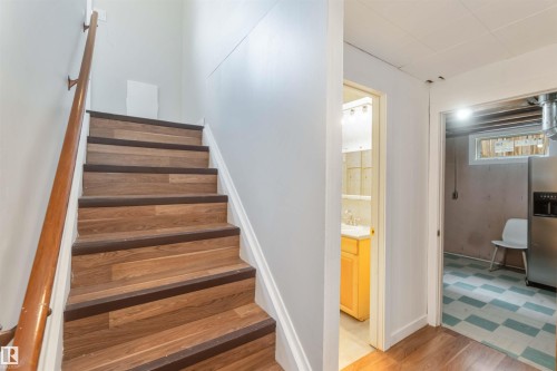 The property features a staircase with wood-look risers and treads, complemented by a wooden handrail - 12121 38 Street, Edmonton, AB - Indoor Photo Showing Other Room