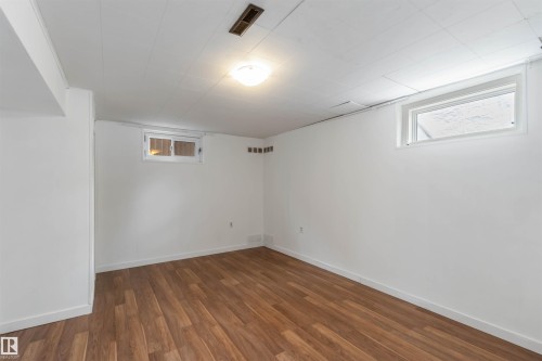 This versatile room features warm-toned hardwood flooring, white walls, and a white ceiling - 12121 38 Street, Edmonton, AB - Indoor Photo Showing Other Room