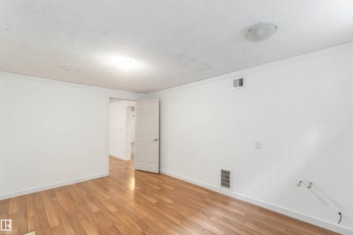 This room features wood flooring, white walls, and a white interior door - 12121 38 Street, Edmonton, AB - Indoor Photo Showing Other Room