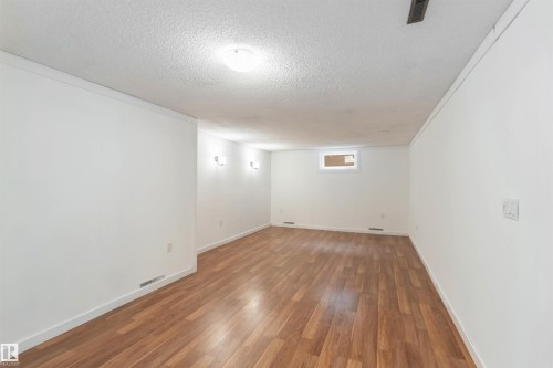 This room features light wood flooring, white walls, and a white ceiling with a flush-mounted light fixture - 12121 38 Street, Edmonton, AB - Indoor Photo Showing Other Room