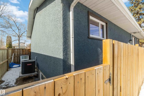 The property features a stucco exterior, a white window frame, and a wooden fence - 12121 38 Street, Edmonton, AB - Outdoor With Exterior