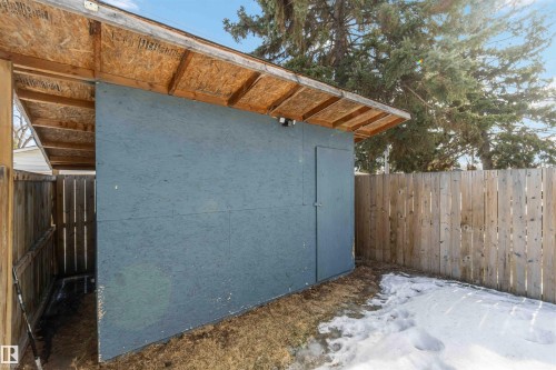 This property features a sturdy wooden fence and an outdoor storage structure with a shed and an open-sided covered area - 12121 38 Street, Edmonton, AB - Outdoor
