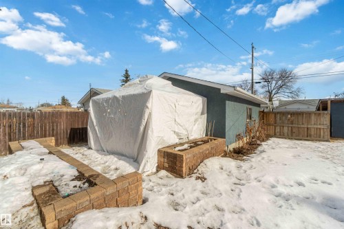 The property includes a fenced backyard with a detached structure, a blue exterior wall, and brick planters - 12121 38 Street, Edmonton, AB - Outdoor