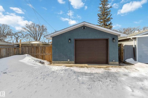 The property includes a detached garage with a dark brown overhead door and blue exterior - 12121 38 Street, Edmonton, AB - Outdoor