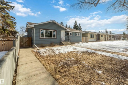 The property features a blue exterior, a front yard with partial snow cover, and a concrete pathway leading to the entrance - 12121 38 Street, Edmonton, AB - Outdoor