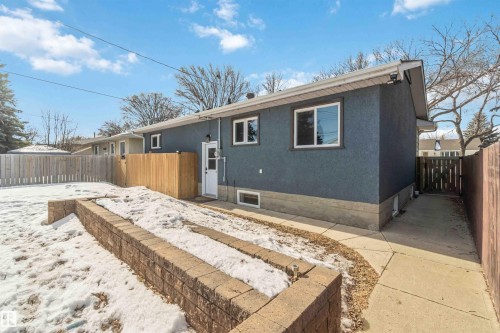 The property features a private backyard with a solid wooden fence, a concrete patio area, and a brick retaining wall - 12121 38 Street, Edmonton, AB - Outdoor