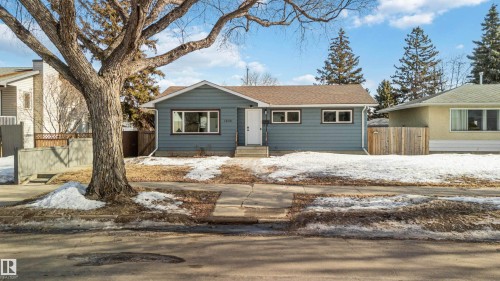 The property features a ranch-style exterior with blue siding and white trim, set back from the street - 12121 38 Street, Edmonton, AB - Outdoor