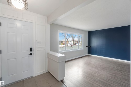 The property entrance features a white paneled door with dark hardware, recessed lighting, and tiled flooring - 12121 38 Street, Edmonton, AB - Indoor Photo Showing Other Room