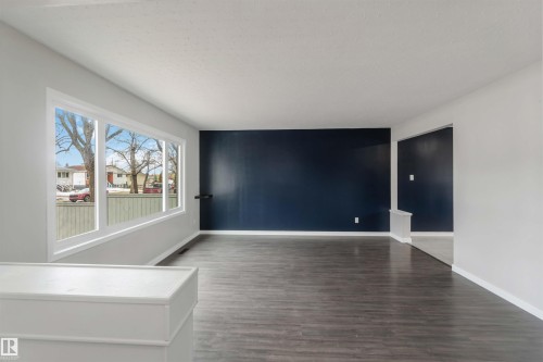 Living area featuring hardwood style flooring, a bay window with white trim, and a striking accent wall - 12121 38 Street, Edmonton, AB - Indoor