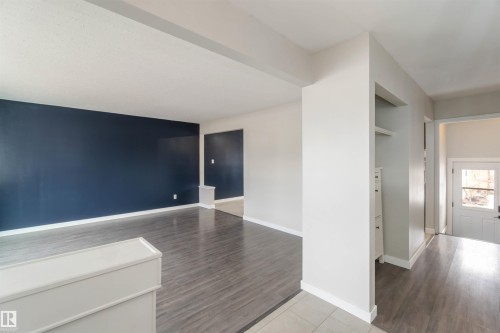 The property features an interior with wood-look flooring and a prominent accent wall - 12121 38 Street, Edmonton, AB - Indoor Photo Showing Other Room