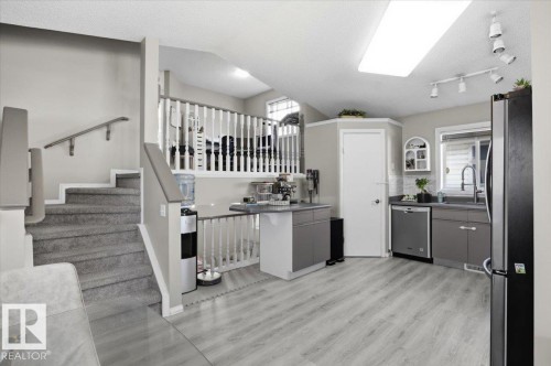 The property features a kitchen with light-colored flooring, gray cabinetry, and a stainless steel dishwasher and refrigerator - 5837 162A Avenue, Edmonton, AB - Indoor