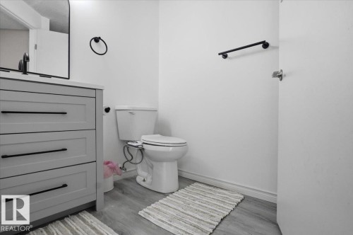 The bathroom features a modern vanity with three drawers and matte black hardware, a toilet, and light-toned flooring - 5837 162A Avenue, Edmonton, AB - Indoor Photo Showing Bathroom