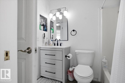 Bathroom featuring a white toilet, a white vanity with a black faucet, and a mirror with a light fixture above it - 5837 162A Avenue, Edmonton, AB - Indoor Photo Showing Bathroom