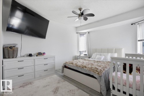 This bedroom features light-colored walls and flooring, a ceiling fan, and two windows providing natural light - 5837 162A Avenue, Edmonton, AB - Indoor Photo Showing Bedroom