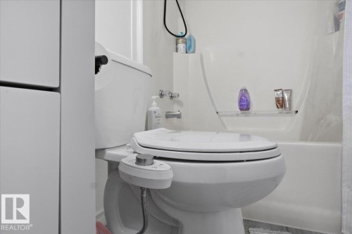 The bathroom features a toilet with an integrated bidet, and a bathtub with built-in shelving - 5837 162A Avenue, Edmonton, AB - Indoor Photo Showing Bathroom