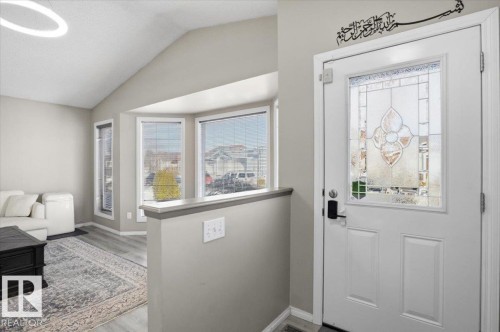 Welcoming entryway featuring a decorative glass panel door and a view into the living area with vaulted ceilings and large bay windows - 5837 162A Avenue, Edmonton, AB - Indoor Photo Showing Other Room