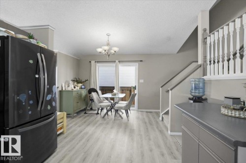 Open concept living area featuring light-toned flooring, a staircase with white spindles, and a sliding glass door leading to the exterior - 5837 162A Avenue, Edmonton, AB - Indoor Photo Showing Dining Room