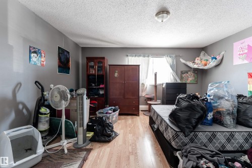 This room features hardwood flooring, a ceiling-mounted light fixture, and a window with white curtains - 2 10737 116 Street, Edmonton, AB - Indoor