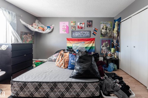 This room features a window, light-colored flooring, and a white closet with bifold doors - 2 10737 116 Street, Edmonton, AB - Indoor Photo Showing Bedroom