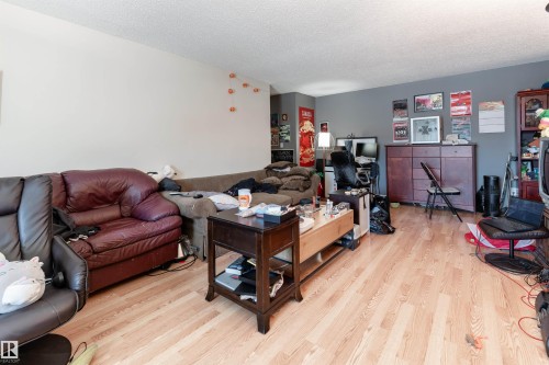 The living area features light-colored hardwood flooring and a ceiling with a textured finish - 2 10737 116 Street, Edmonton, AB - Indoor