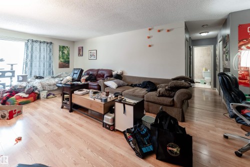 This room features light-toned flooring, a light-colored ceiling, and white wall paint - 2 10737 116 Street, Edmonton, AB - Indoor Photo Showing Living Room
