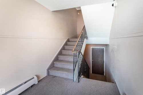 Staircase featuring carpeted steps and a wrought iron railing - 2 10737 116 Street, Edmonton, AB - Indoor Photo Showing Other Room