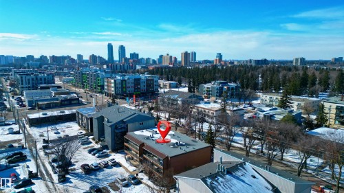 Aerial view showcasing the property's location within a developed neighborhood, featuring surrounding buildings and distant city skyline - 2 10737 116 Street, Edmonton, AB - Outdoor With View