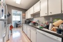 Kitchen featuring white cabinetry, grey subway tile backsplash, and light wood flooring - 2 10737 116 Street, Edmonton, AB  - Indoor Photo Showing Kitchen 