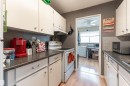 The kitchen features white cabinetry, dark countertops, and a subway tile backsplash - 2 10737 116 Street, Edmonton, AB  - Indoor Photo Showing Kitchen 