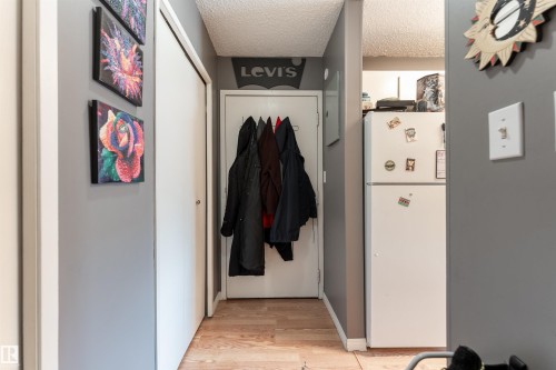 Hallway featuring light wood-style flooring and a white refrigerator - 2 10737 116 Street, Edmonton, AB - Indoor