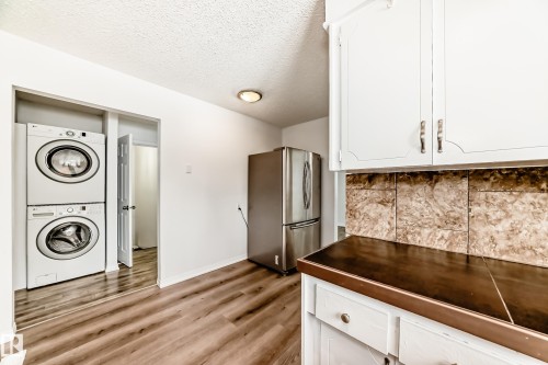 Kitchen area featuring white cabinetry, a dark countertop, and a tiled backsplash - 4312 43 Avenue, Leduc, AB - Indoor