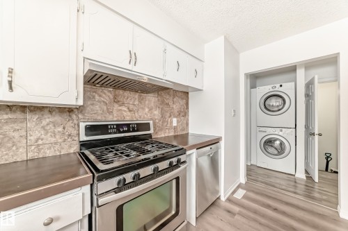 The kitchen features white cabinetry, stainless steel appliances, and a tiled backsplash - 4312 43 Avenue, Leduc, AB - Indoor Photo Showing Kitchen