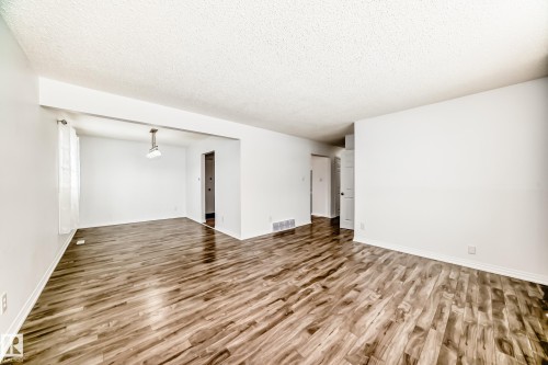 Spacious open concept living area featuring wood-look flooring and white walls - 4312 43 Avenue, Leduc, AB - Indoor Photo Showing Other Room