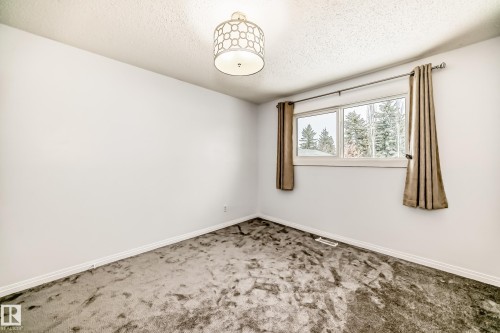 This room features a window with a view of trees, a ceiling light fixture, and light-colored walls - 4312 43 Avenue, Leduc, AB - Indoor Photo Showing Other Room