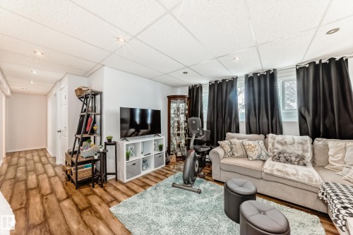 Living area with wood-look flooring and a light-colored area rug - 4312 43 Avenue, Leduc, AB - Indoor Photo Showing Living Room