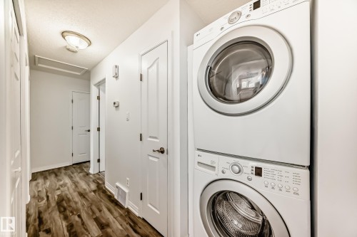 This hallway features hardwood-style flooring, white paneled doors, and a ceiling-mounted light fixture - 4312 43 Avenue, Leduc, AB - Indoor Photo Showing Laundry Room