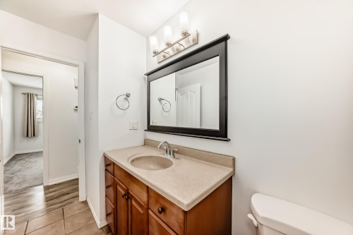 Bathroom featuring a vanity with a light-colored countertop and a mirror with a dark frame, illuminated by an overhead light fixture - 4312 43 Avenue, Leduc, AB - Indoor Photo Showing Bathroom