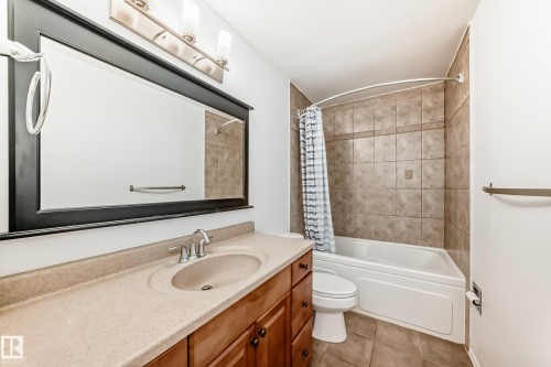 Bathroom featuring a vanity with a built-in sink, a large mirror, and a bathtub with tiled walls - 4312 43 Avenue, Leduc, AB - Indoor Photo Showing Bathroom