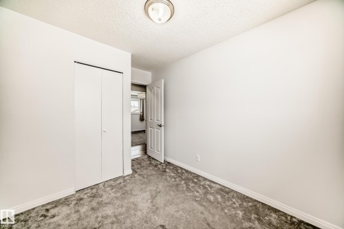 This room features light-colored walls, gray carpet, and a bi-fold closet door - 4312 43 Avenue, Leduc, AB - Indoor Photo Showing Other Room