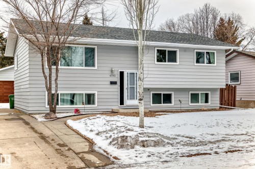 The property features gray siding and a dark shingled roof, with white window frames throughout - 4312 43 Avenue, Leduc, AB - Outdoor