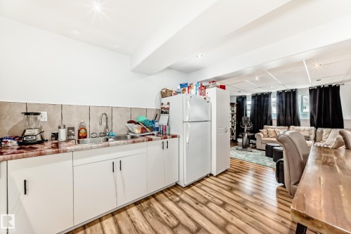 Utility kitchen with a stainless steel sink, light-colored cabinetry, and a full-size refrigerator - 4312 43 Avenue, Leduc, AB - Indoor Photo Showing Kitchen With Double Sink