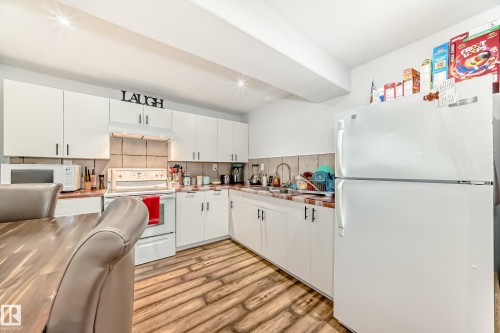 The kitchen features white cabinetry, a white refrigerator, and a white oven with a microwave - 4312 43 Avenue, Leduc, AB - Indoor Photo Showing Kitchen With Double Sink