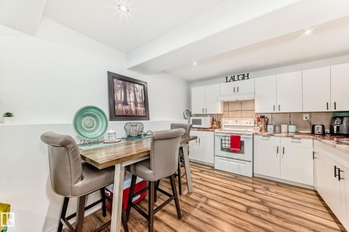The kitchen features white cabinetry, a white stove, and light-colored countertops - 4312 43 Avenue, Leduc, AB - Indoor Photo Showing Kitchen