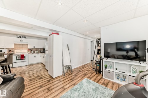 This property features a kitchen with white cabinetry and a backsplash, complemented by wood-look flooring - 4312 43 Avenue, Leduc, AB - Indoor