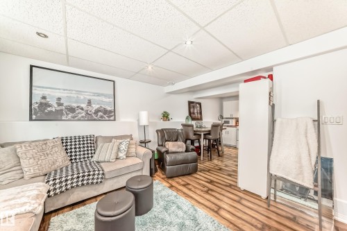 This versatile living area features hardwood flooring, a drop ceiling with recessed lighting, and a neutral color palette - 4312 43 Avenue, Leduc, AB - Indoor Photo Showing Living Room
