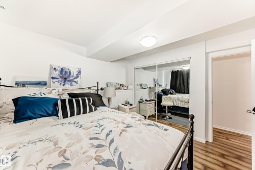 Bedroom featuring light wood flooring, white walls, and a mirrored closet - 4312 43 Avenue, Leduc, AB - Indoor Photo Showing Bedroom