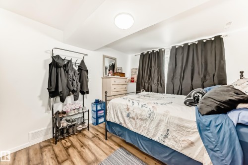 The property features hardwood style flooring, a neutral color palette, and a ceiling-mounted light fixture - 4312 43 Avenue, Leduc, AB - Indoor Photo Showing Bedroom