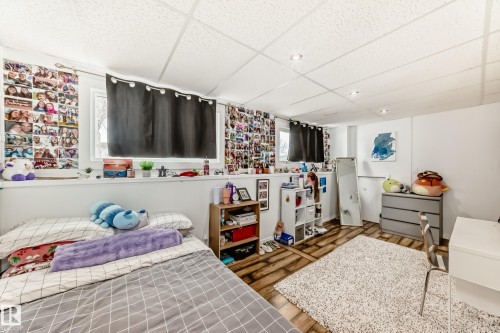 This room features a window with dark curtains, a textured ceiling with recessed lighting, and wood-style flooring - 4312 43 Avenue, Leduc, AB - Indoor Photo Showing Bedroom