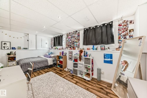 The property features a room with wood-style flooring and a drop ceiling - 4312 43 Avenue, Leduc, AB - Indoor