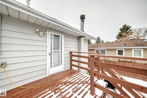 The property features a wooden deck with a brown railing, accessible via a white door with decorative glass - 4312 43 Avenue, Leduc, AB - Outdoor With Deck Patio Veranda With Exterior